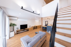 広々としたLDK空間で、木目調の床とシンプルなインテリアが調和し、モダンな印象を与える。階段がアクセントになっている。