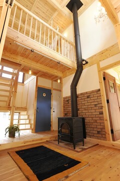 高い天井と薪ストーブが特徴的な玄関ホール。木の温もりが感じられ、開放感あふれるスペースとなっている。