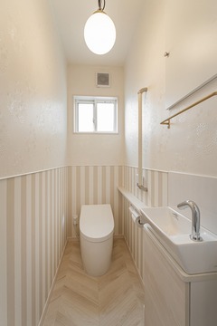 コンパクトながらも洗練されたトイレ空間。ストライプの壁紙がアクセントとなり、明るい室内を演出している。