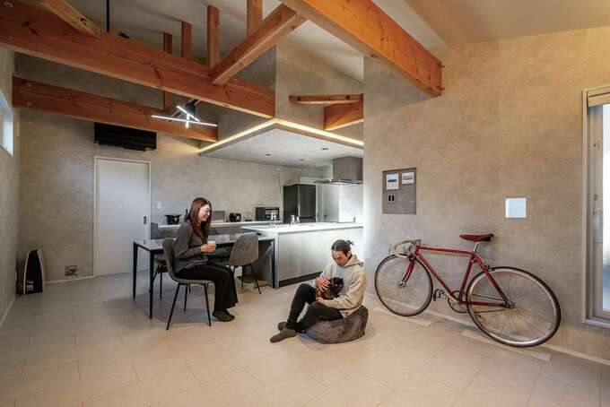 20畳の2階LDKは、吹き抜けを採用したことで、より開放的に感じられる。タイルのように見えるフローリングがおしゃれな空間。HEAT20 G2相当の高い断熱性能を備えており、アパート時代とは比較にならないほど暖かく、快適に過ごせるとお二人も笑顔