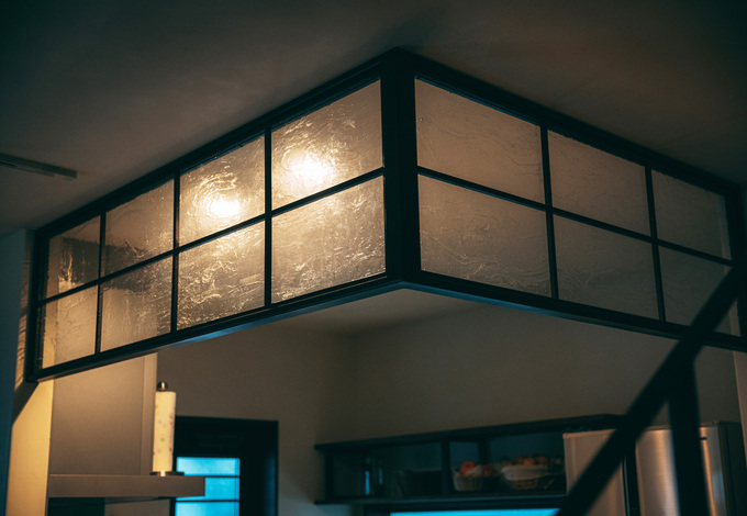 キッチンの垂れ壁の代わりに、アイアンの枠にガラスを貼ったオリジナルのパーティションを採用。曇りガラスに照明の灯りがほんのり透けて、大正浪漫の情緒を醸し出す