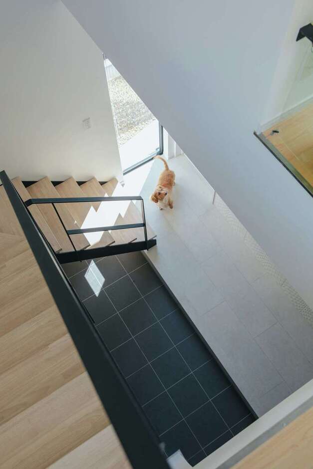 横長の玄関土間の上にスリップ階段を設置。庭に面してFIX窓を設け、玄関の空間に広がりを持たせた