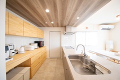 ゆったりとしたスペースを持つキッチン。ナチュラルな木目調の収納が並び、明るい照明が温かみを演出する。