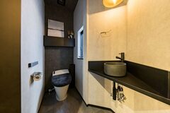 モダンなデザインのトイレ空間。洗練されたダークトーンが落ち着いた雰囲気を醸し出し、機能性とデザイン性を兼ね備えている。【iDpluss アイディープラス】
