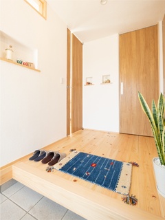 自然素材に包まれた玄関ホールは、飾りニッチや天井まで届くハイドアなどデザイン性豊かな空間。