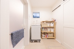 機能的なランドリールーム。洗濯機と収納棚が効率よく配置され、作業がしやすい空間。シンプルで清潔感のあるデザイン。