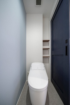 シンプルで清潔感のあるトイレ空間。柔らかな色合いと収納棚がポイントで、機能性とデザイン性を両立している。【マルモホーム】