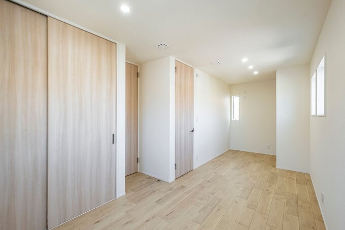 シンプルで使いやすい空間の子ども部屋。明るい木目調の床と落ち着いた壁紙が心地よい雰囲気を演出している。ドアが二つ付いており、将来的に二つに分けることも可能