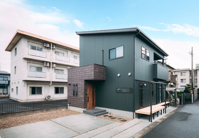 ダークグリーンの外壁が個性的な外観。突出した玄関部分の外壁を木目調にしてアクセントを付けた。建物の南面にはウッドデッキを確保