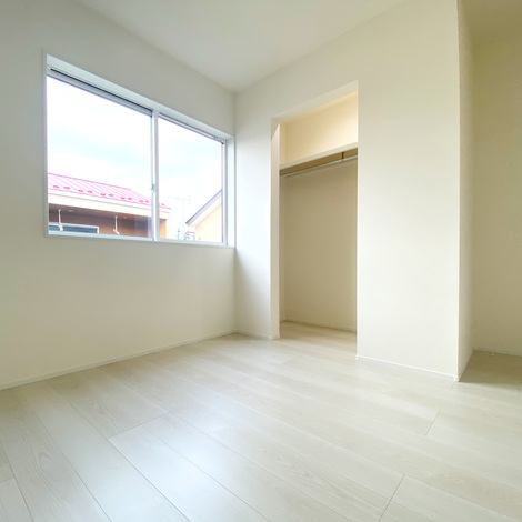 明るい自然光が差し込むシンプルな居室。窓の外には建物の一部が見え、広々とした空間が広がっている。