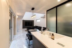 キッチンの後ろは天井まで高さがある4枚の引き戸でスッキリ目隠し。フラットなキッチンが空間を広く感じさせる。