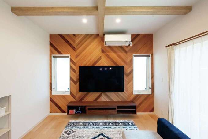 無垢ヘリンボーンのアクセントクロスは標準仕様。TVボードは造作。南側に隣家が建っているため、TVの両サイドにも窓を設けて光を確保