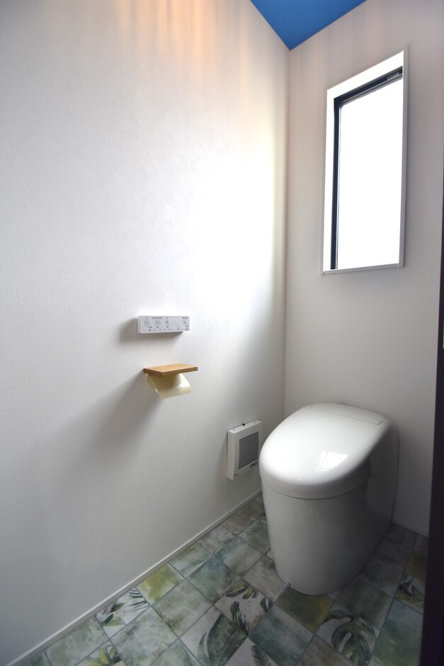 1階トイレは、天井の鮮やかなブルーのクロスと、オシャレなタイルが印象的。オーナー様のセンスが感じられる。