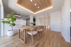 木の温もりが感じられるモダンなダイニング。ナチュラルな照明と観葉植物が落ち着いた雰囲気を演出している。シンプルかつスタイリッシュなデザインが魅力的。