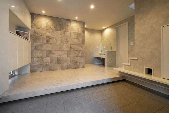 2世帯共用のエントランスは、ラグジュアリーなテイストに。正面の壁は消臭効果の高いエコカラット。右手の壁にある猫穴の奥は、猫専用のトイレ。将来、ベビーカーを置いたり、大型犬を飼ったりしても狭くならないよう、あらかじめ広く計画した