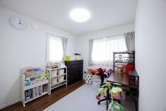 明るく開放的な子ども部屋。おもちゃや本が整然と並び、遊びや学びの空間として活用できる。