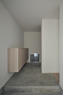 モルタルの土間が奥まで続く玄関。土間の奥を右に曲がると趣味の部屋が設けてある。玄関収納を宙に浮くスタイルにしたことで、土間に広がりが生まれ、掃除もしやすくなった
