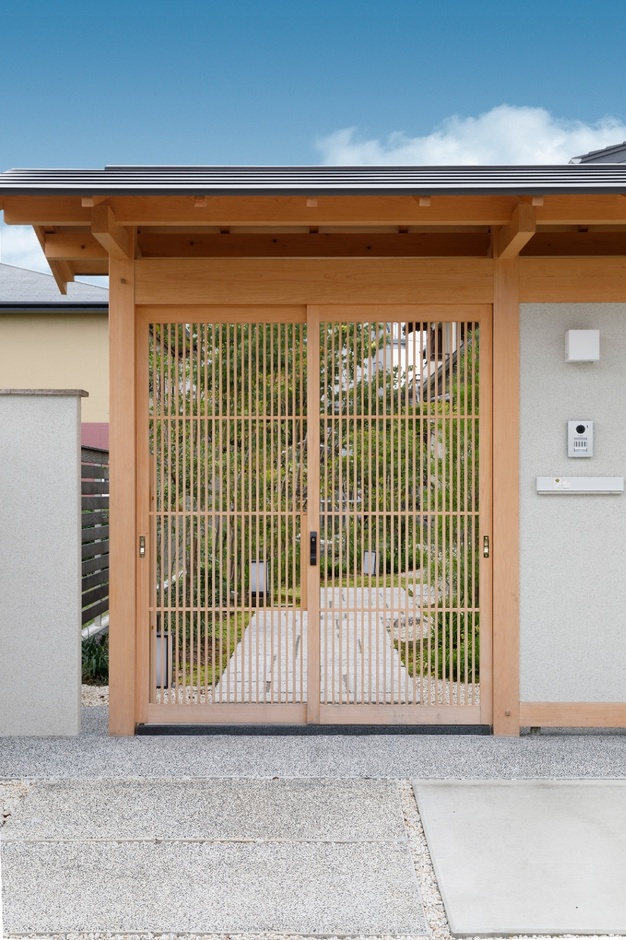 和風の趣を感じさせる門構え。木製の格子戸が上品で、伝統と現代的な感覚が見事に融合している。