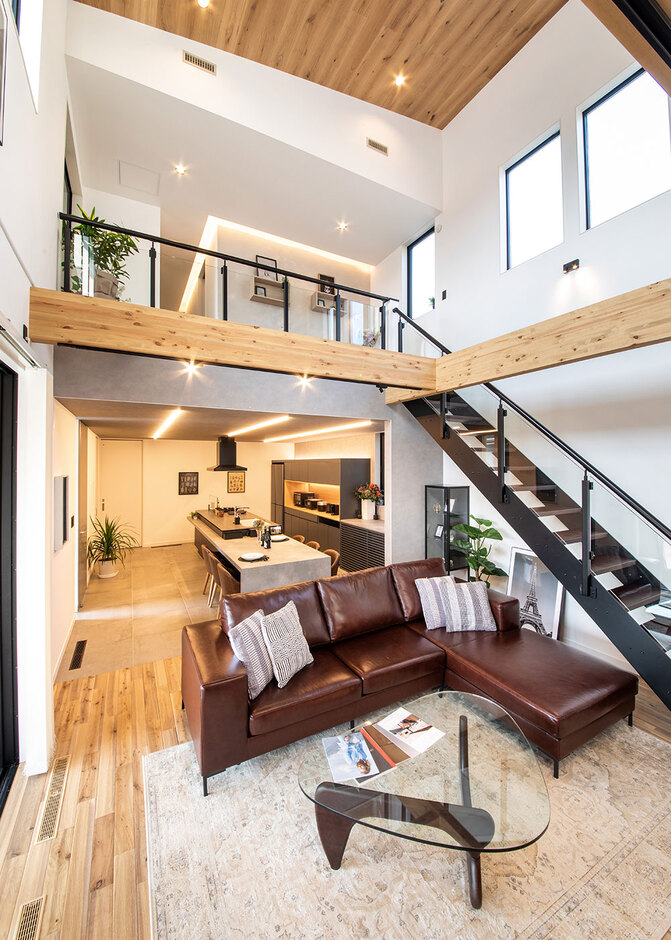 nattoku住宅【沼津市東椎路848-2・モデルハウス】12.5畳の吹抜けが気持ちいい開放的なリビング。オリジナルの無垢フローリング（JHON）、漆喰の塗り壁、革張りのソファ（MOTTA）は『nattoku』の標準仕様。これほどの大空間でも全館空調システムにより上下階の温度差がなく、夏も冬も薄着で快適に過ごせる