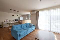 ナチュラルカラーで整えたリビングは、L字形の間取りでゆるやかにゾーニング。ソファのデニムブルーが差し色