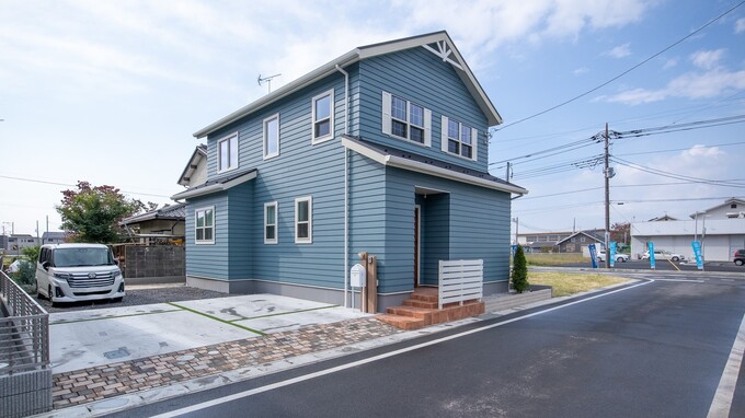 2階建ての美しい外観を持つ住宅。ブルーの外壁と白い窓枠が爽やかさを演出し、全体のデザインを引き立てている。