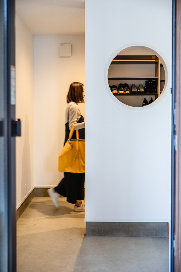 土間のある玄関ホール。靴が好きな奥さまのために、シューズクローゼットを広めにつくった。丸い穴を開けて遊び心を演出
