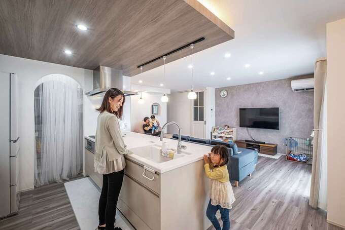 キッチンの天井に木調のパネルと間接照明を採用して、スタイリッシュな空間に。アーチの向こうはパントリー。その先にファミリークローゼットを設けている