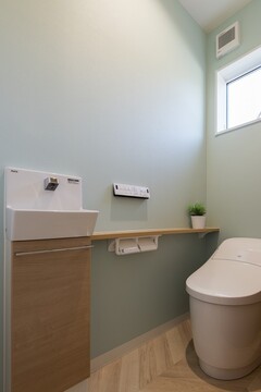 清潔感溢れるトイレは、ペールグリーンの壁が優しい印象を与える。コンパクトな手洗いスペースも完備【トキワハウス デザイン アンド ビルド（常盤工業）】