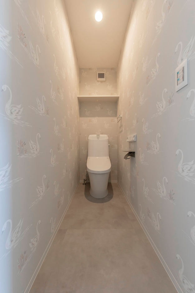 柔らかな壁紙が施されたトイレ空間。照明が優しく空間を照らし、落ち着く雰囲気を醸し出している。
