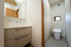 シンプルで機能的なトイレと洗面スペースが並ぶ。明るい色調が清潔感を演出し、快適な使用感を提供する。【ユースタイルハウス　上村建設】