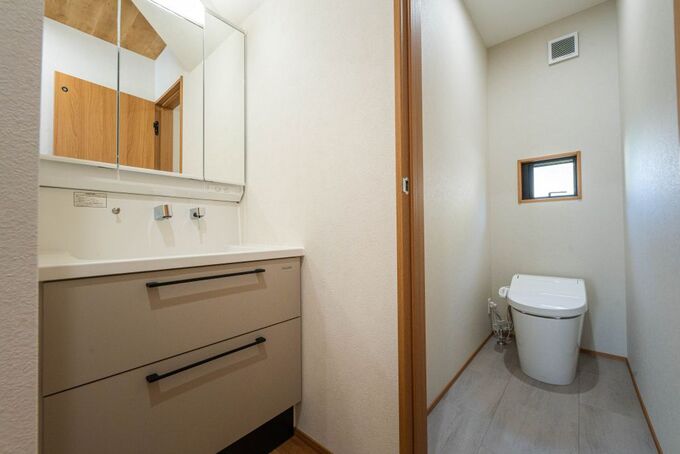 シンプルで機能的なトイレと洗面スペースが並ぶ。明るい色調が清潔感を演出し、快適な使用感を提供する。