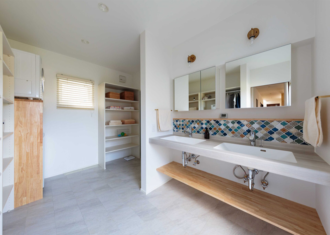 キッチンの背面奥にある水回りスペース。「3人の娘が同時に身支度できるように」と2つの洗面ボウルを持つワイドな洗面を造作した。壁に貼ったモザイクタイルがアクセントに