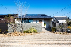 平屋のように見えるどっしりとした外観デザイン。片流れの屋根に太陽光発電を搭載し、光熱費は毎月黒字に。エクステリアにもコストをかけ、建物とのバランスが取れた美しい住まいが完成した【リンクホーム】