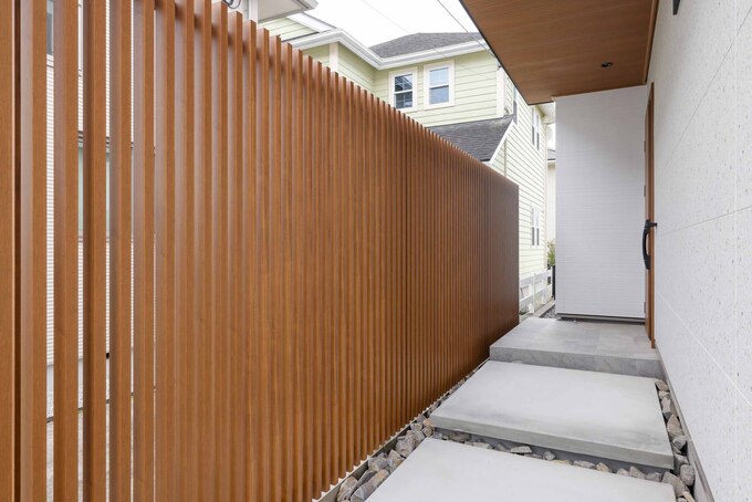 モダンなデザインの通路。木目調のフェンスが家のプライバシーを守りながら、上品な雰囲気を醸し出している。