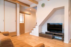 階段下のニッチをテレビコーナーに活用。階段の壁は途中からとし、視線が奥まで抜ける。建具もすべて職人の手作り【仲田工務店】