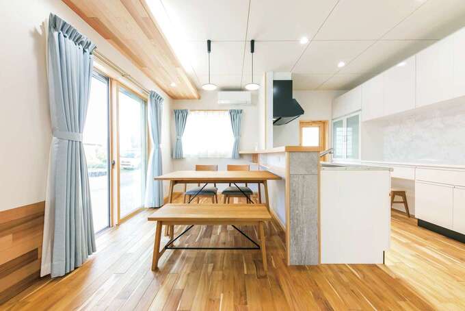 ２面開口で明るいダイニングキッチン。照明が仕込まれた天井板はレッドシダー