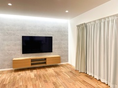 シンプルでモダンなリビングルーム。壁掛けテレビと木製のキャビネットが調和し、落ち着いた空間を演出している。【小野田産業～designers house project～】