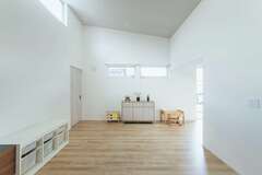 勾配天井によって開放感が倍増したリビング。高窓から明るさも十分に確保した。子どもがのびのび遊べるように当分はソファを置かない予定。植物の作業スペースともつながり、移動もスムーズだ