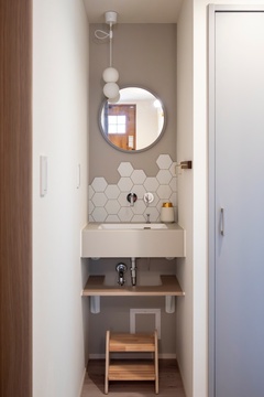 リズミカルに配置したヘキサゴンタイル（名古屋モザイク）が、さりげない存在感を添えるセカンド洗面台。玄関から2階への動線上に設け、帰宅後すぐに手を洗えるように。自然と子どもたちの手洗い習慣も身に付きます。