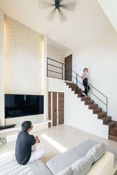 高さ5mもある吹き抜けの大空間リビング。清潔感のある白で統一し、リゾートホテルのような優雅な暮らしを楽しむ。テレビの背面は調湿性にすぐれたエコカラットを贅沢に使用