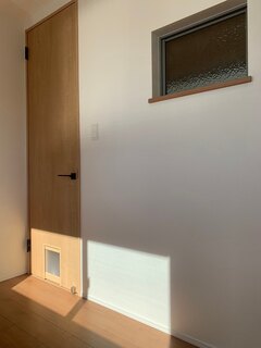 小さな通り抜け口があるドアが特徴のペット用スペース。明るい木材のフローリングが温かみを演出し、窓からの自然光が心地よい環境を提供【プロスパーライフ】