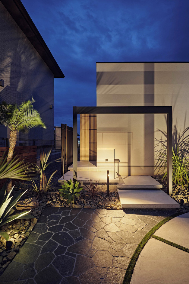 外構には黒いゲートや南国風の植栽を用い、シンプルを極めた外観をリゾートチックに彩っている