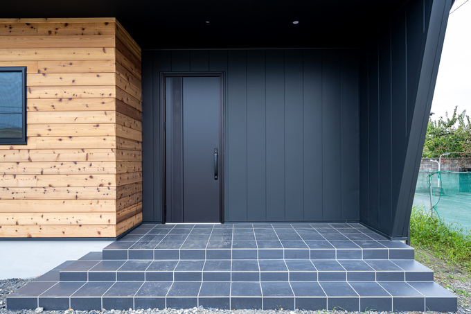 木素材と黒のコントラストが印象的な玄関エリア。広々としたステップとシンプルなデザインがモダンな雰囲気を引き立てる。