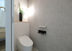 洗面スペースの隣に設けたトイレには、グレーのアクセントクロスを採用。ペンダント照明が安らぎと高級感を演出【丸昇彦坂建設】