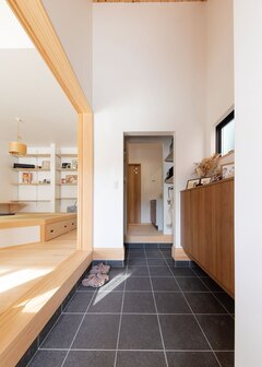 土間玄関から手洗いコーナーへ直結する「ただいま動線」。土間とリビングが曖昧につながり、家族をやさしく出迎える