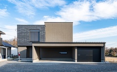 モダンなデザインの二階建て住宅の外観。落ち着いた色合いの外壁と広々としたガレージが特徴で、都市部でも自然とも調和するスタイリッシュな佇まい。【タカオ設計】