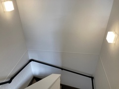 シンプルなデザインの階段スペース。壁に取り付けられたライトが視認性を高め、安全を確保している印象がある。