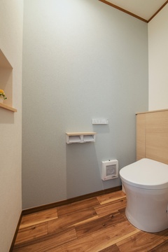 シンプルで清潔感のあるトイレ空間。優しい色合いの壁と木目調のフローリングが、落ち着いた雰囲気を醸し出している。【水田建設】