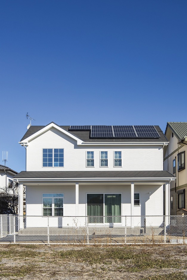 太陽光パネルが設置されたエコな住宅。採光性と通風性が高い大きな窓が特徴で、快適な住まいを提供する。