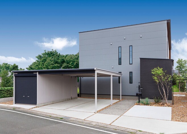 住宅街に突如として現れたオブジェのように見えるスタイリッシュな外観。プライバシーを考慮して、玄関部分を壁と植栽で遮っている。カーポートのデザイン・色にもこだわり、建物とのバランスも絶妙